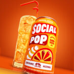 A can of Orange Cream Social Pop next to a full poured glass with curly straw.